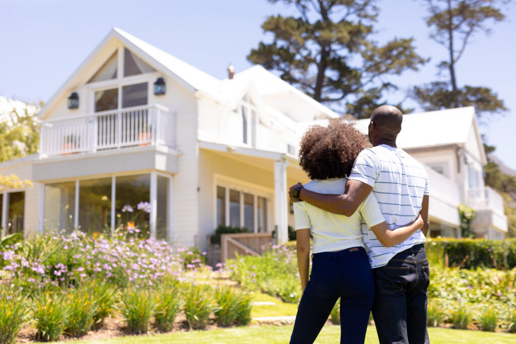 Young couple standing in the garden looking at their house