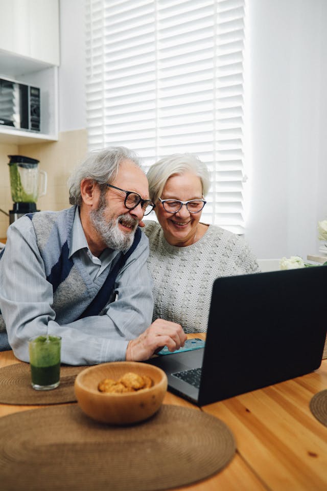 senior couple smiling at a laptop